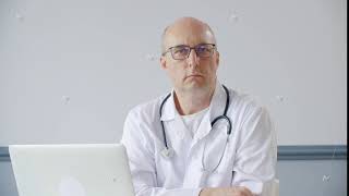 Portrait bald male doctor nodding head sitting on table front laptop in medical office Practitioner [upl. by Jessy]