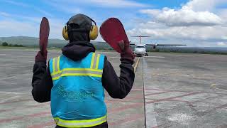 The aircraft marshaller is signaling the ATR72 plane to taxi to the airport ramp [upl. by Carlick]