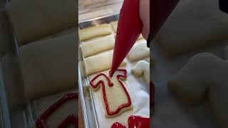 Baker is flooding a graduation gown cut out cookie with royal icing [upl. by Assirolc8]