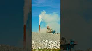 white steam rising up from pipe of small asphalt factory at day time with piles of gravel in a [upl. by Sanbo]